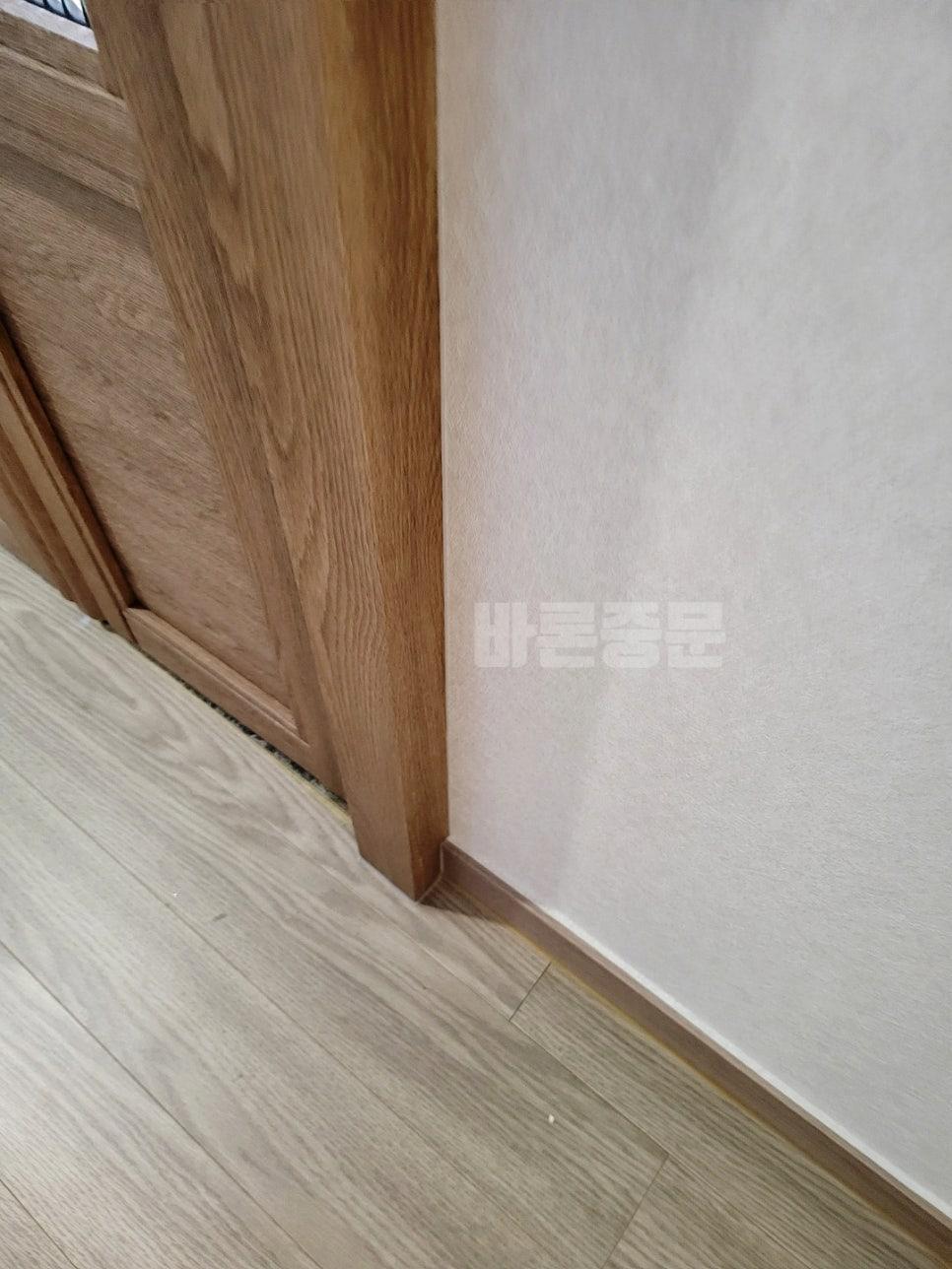 나무 톤 도어와 벽지, 바닥재가 접합되는 지점
