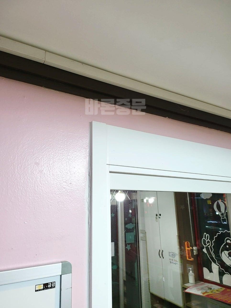 분홍색 벽과 화이트 프레임이 맞닿은 실내 전경