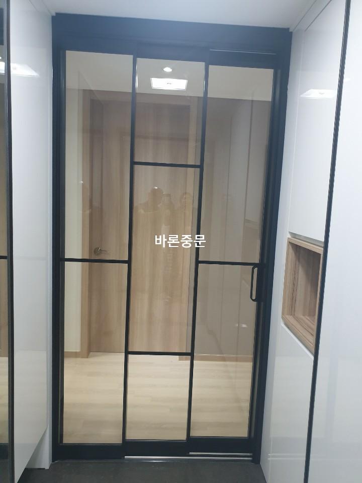 흰색 수납장과 블랙 프레임이 나란히 배치된 복도