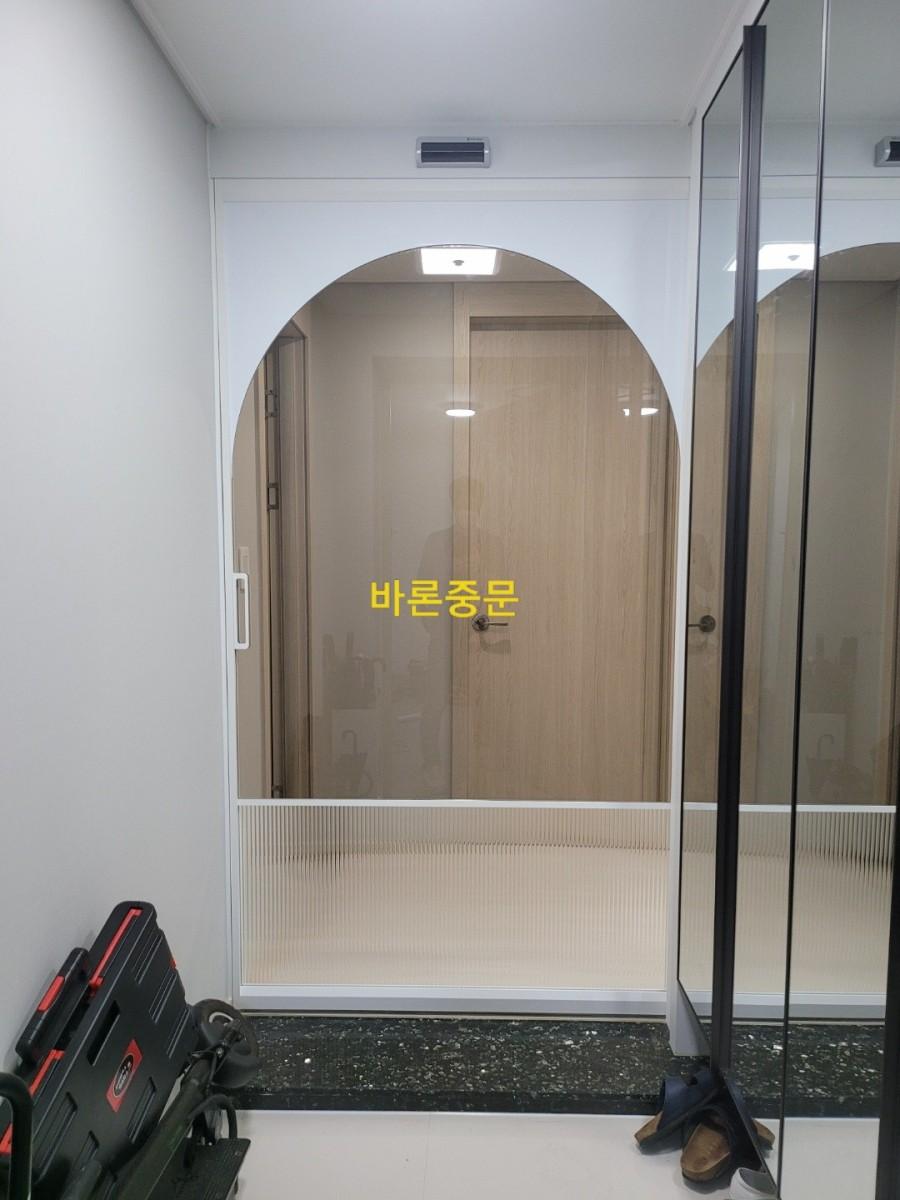 검은색 프레임의 아치형 유리문이 설치된 현관 전경