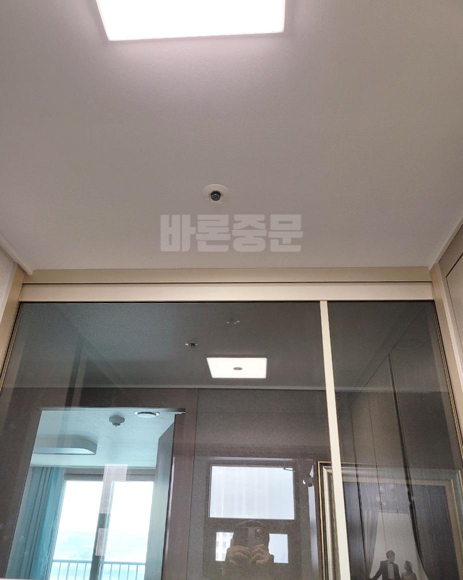 어두운 우드톤 붙박이장 앞의 회색 유리 도어