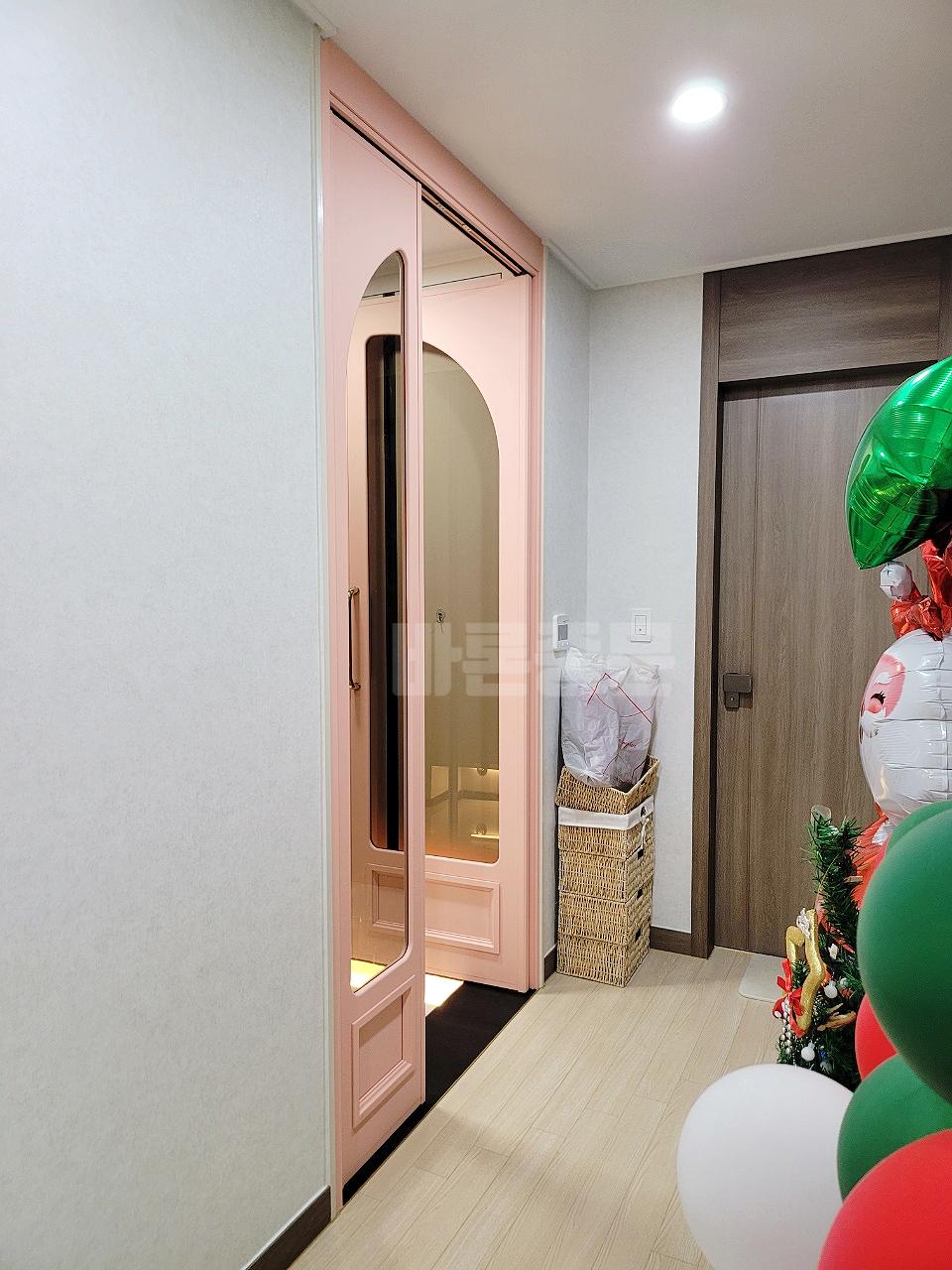 나무 톤의 문과 조화를 이루는 핑크 컬러 아치 도어
