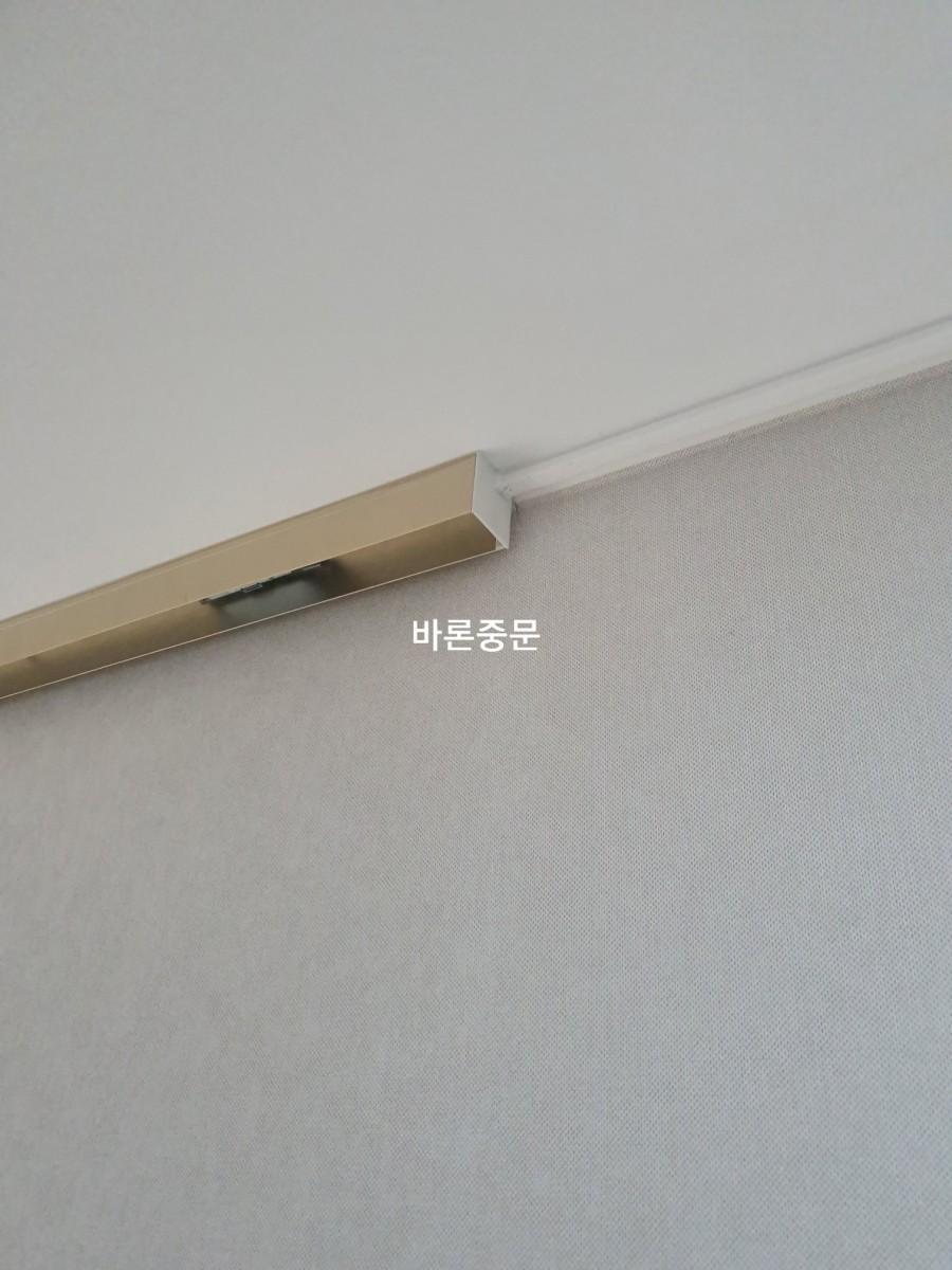 벽면과 천장 접합부의 금속 프레임과 흰색 트림