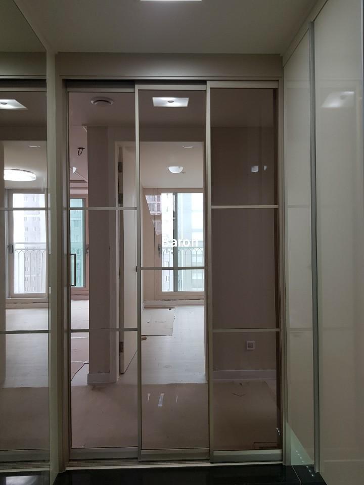 베이지색 벽면과 흰색 마루 위에 설치된 슬라이딩 도어