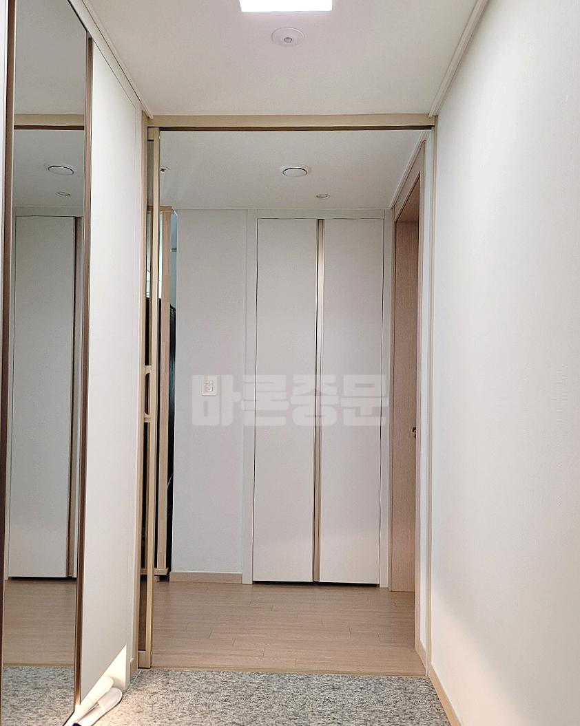 나무 톤 바닥재가 깔린 복도에서 본 유리 도어의 모습