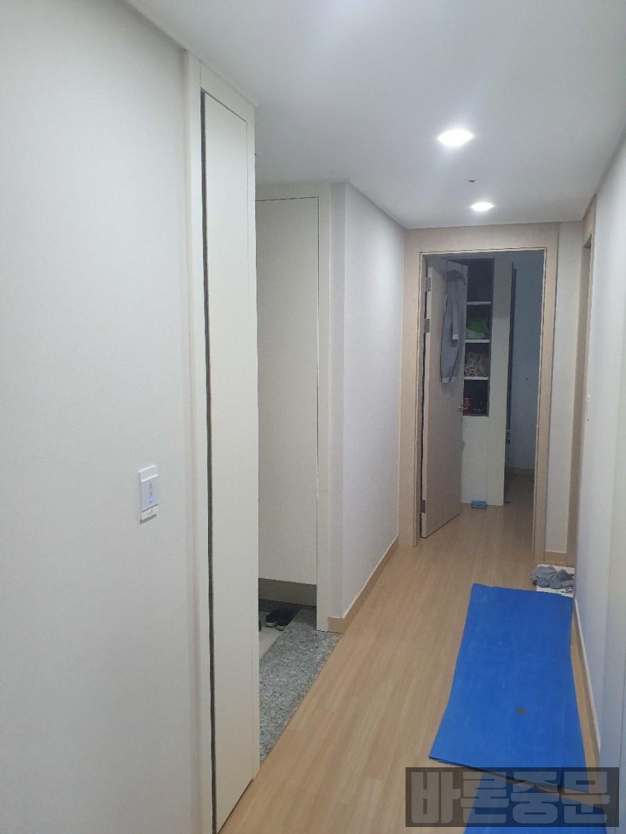 흰 벽면과 목재 바닥 사이에 설치된 도어의 마감 모습