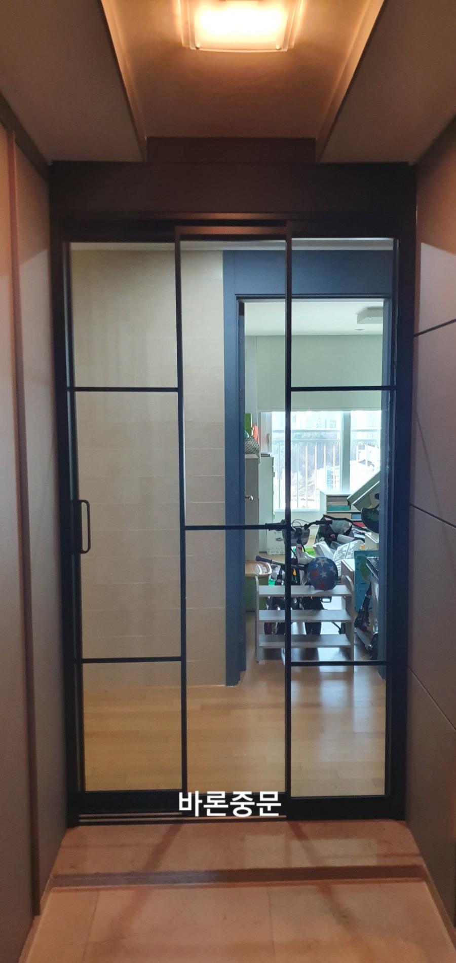 목재 마루 복도에 설치된 검은색 프레임 도어