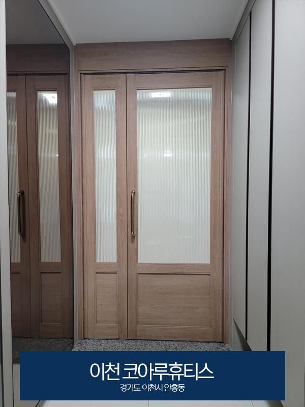 금색 손잡이가 달린 나무 문과 석재 마감 바닥의 모습