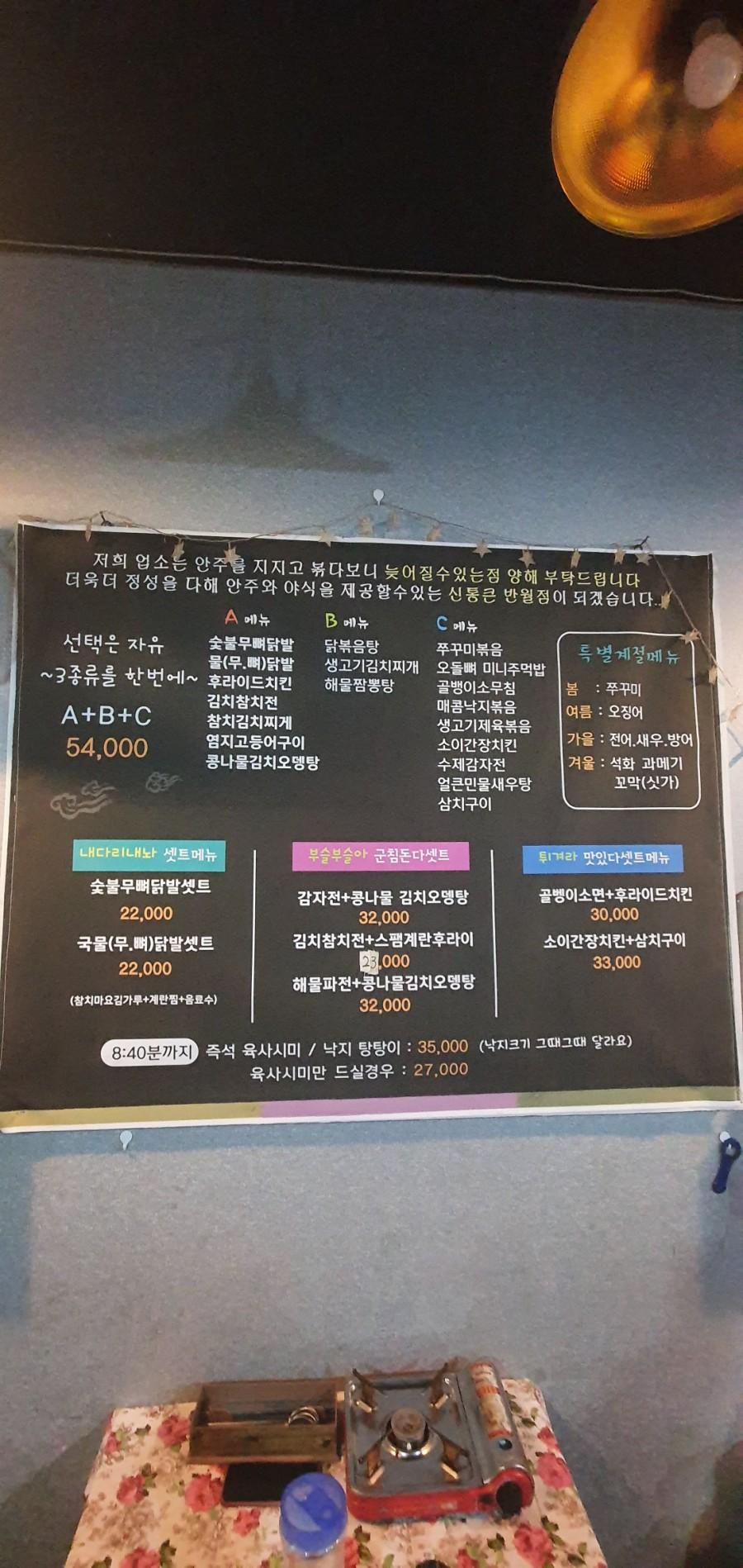 벽면 메뉴판 아래로 보이는 꽃무늬 테이블과 가스레인지