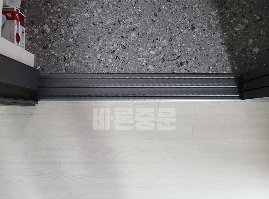 바닥 마감재 사이에 설치된 검은색 도어 트래킹 장치