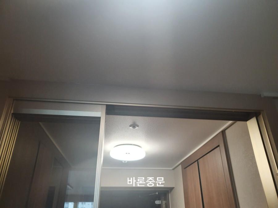 원형 조명 아래 설치된 슬라이딩 도어와 벽면 수납장