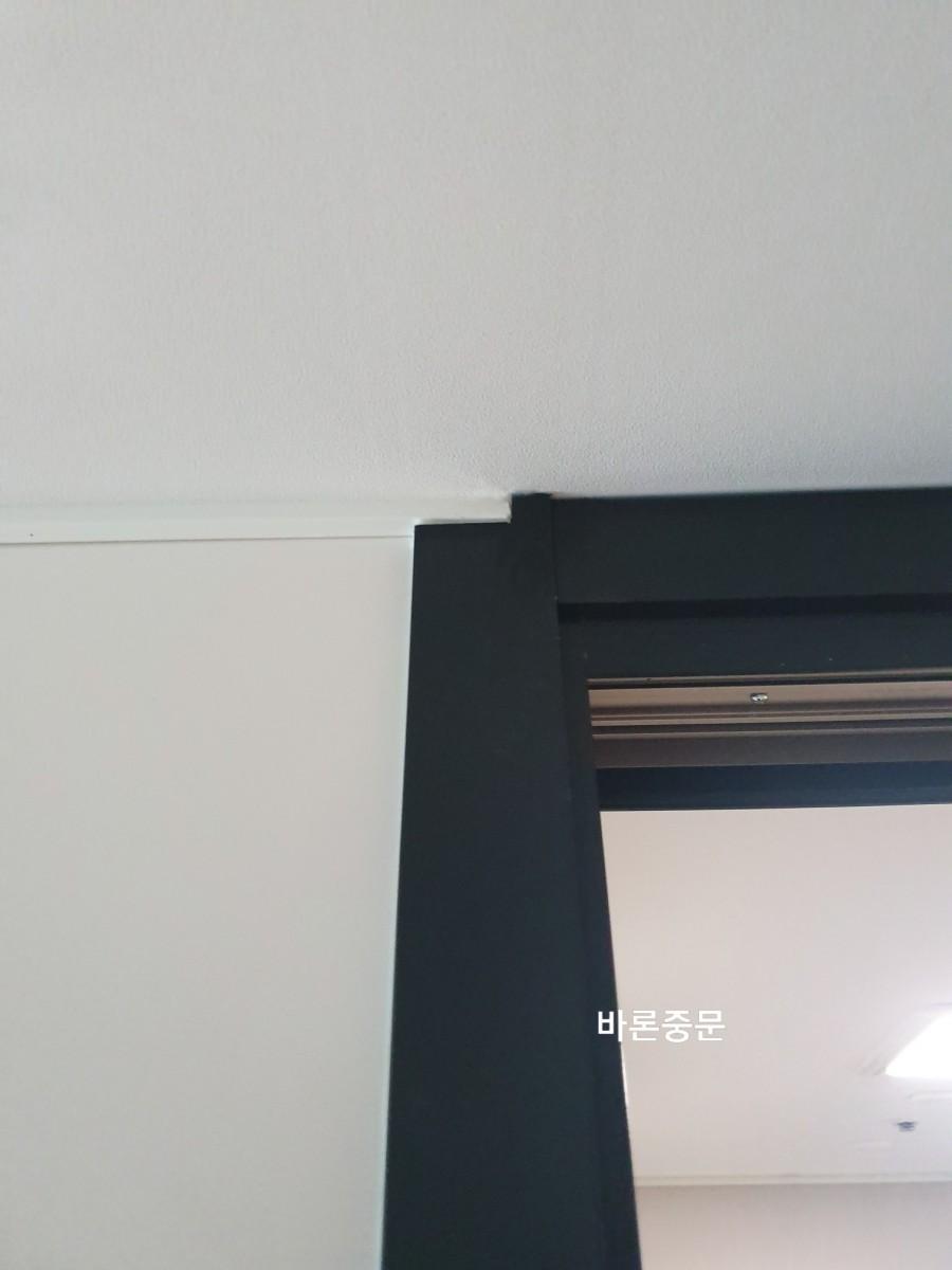 흰 벽과 검은색 도어 프레임의 상단 연결 부위
