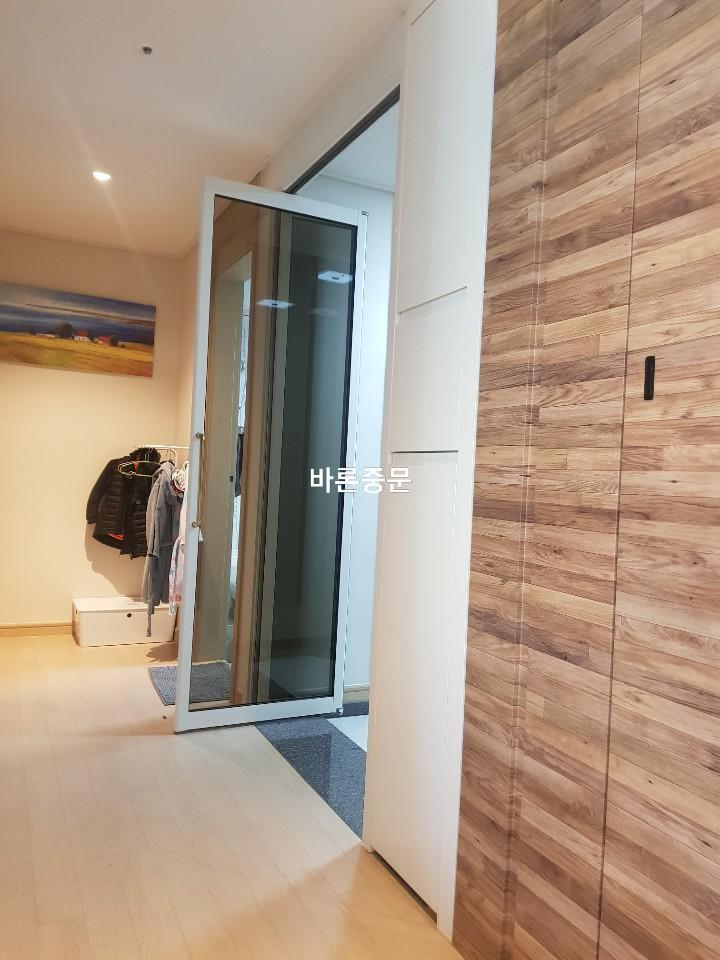 목재 패널 벽과 유리 문이 만나는 복도 공간