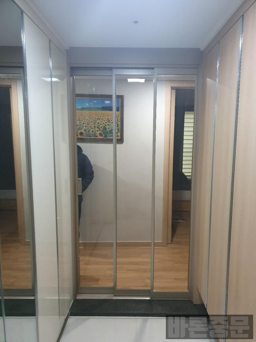 목재 바닥과 수납장 사이에 설치된 유리 슬라이딩 도어