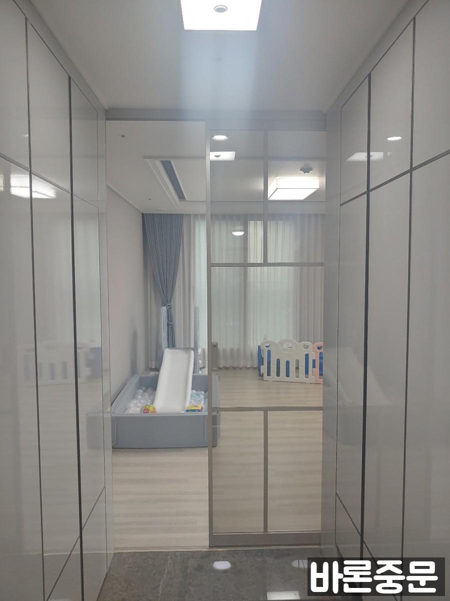 유리문 너머로 보이는 아이의 파란색 놀이 수영장과 블록들