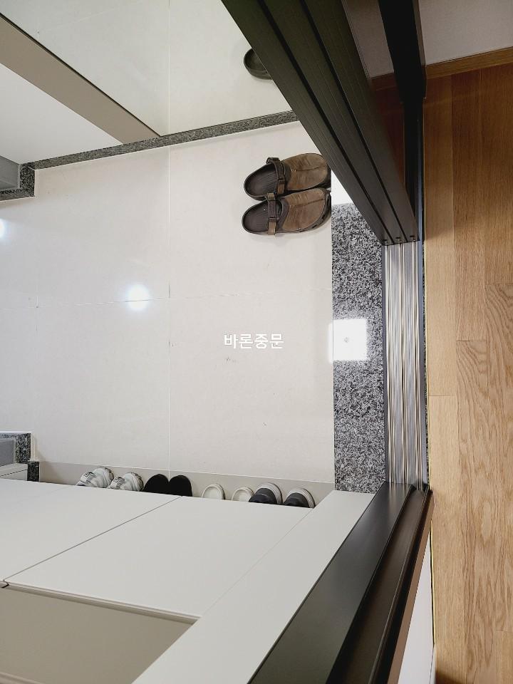 상단 레일과 투명 유리 문이 보이는 현관 측면