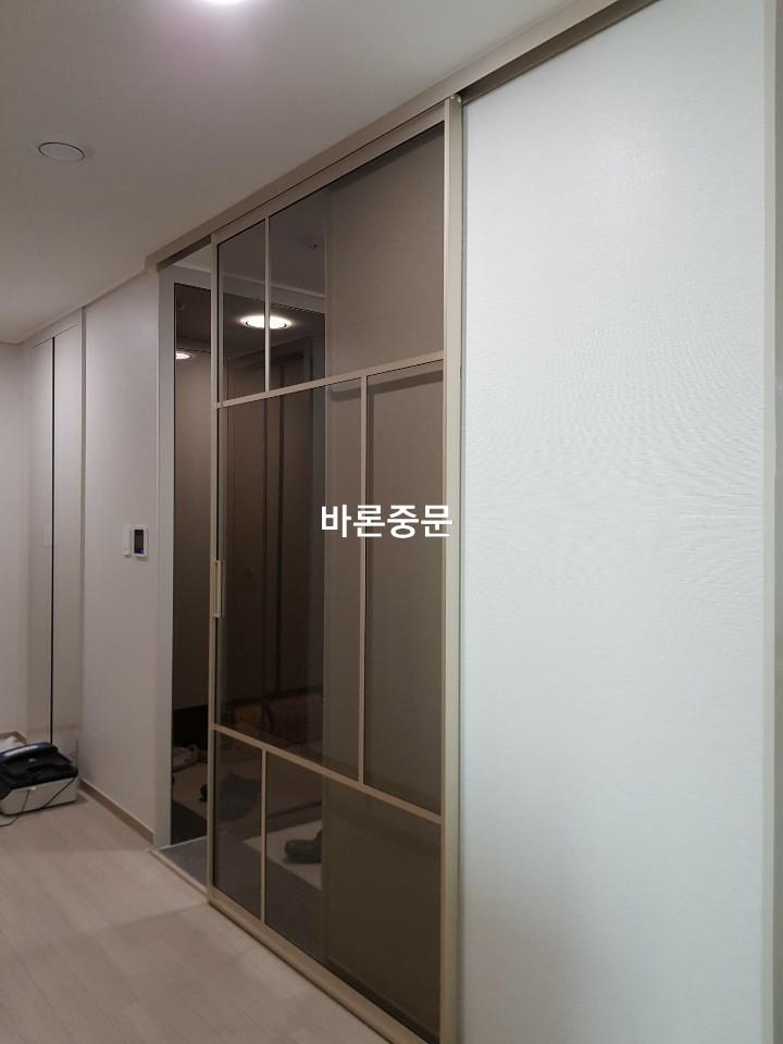 흰색 벽면과 목재 바닥 사이에 설치된 슬라이딩 도어