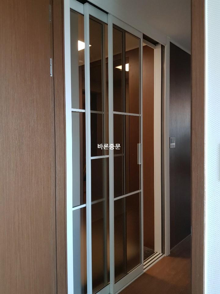 나무 패널 마감벽에 설치된 흰색 프레임 도어