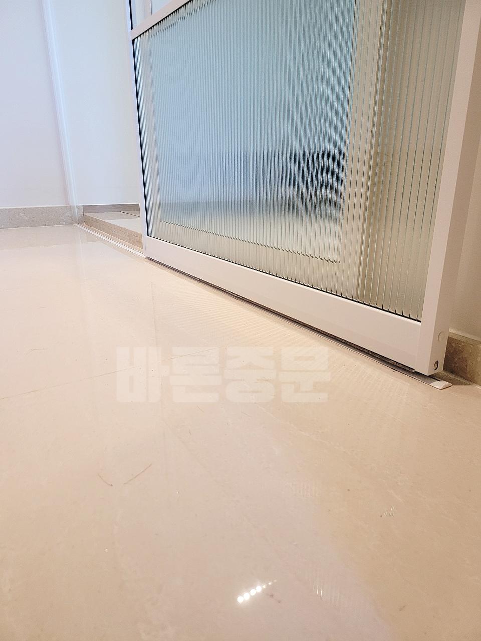 세로줄 패턴의 유리 창호와 베이지색 바닥의 디테일