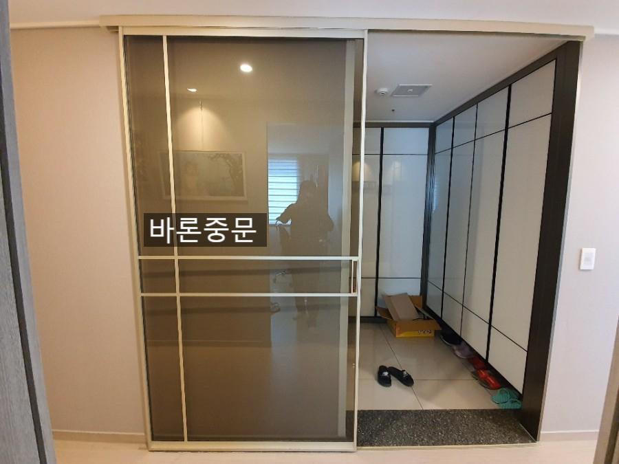 베이지색 벽지와 흰색 타일이 만나는 현관의 도어 모습