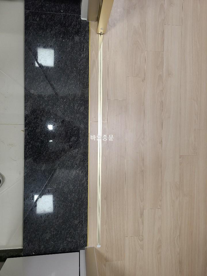 대리석과 목재 바닥이 만나는 경계의 금색 라인 마감