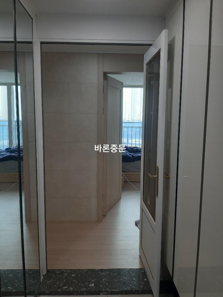 투명 유리 문과 벽면 패널이 맞닿은 복도
