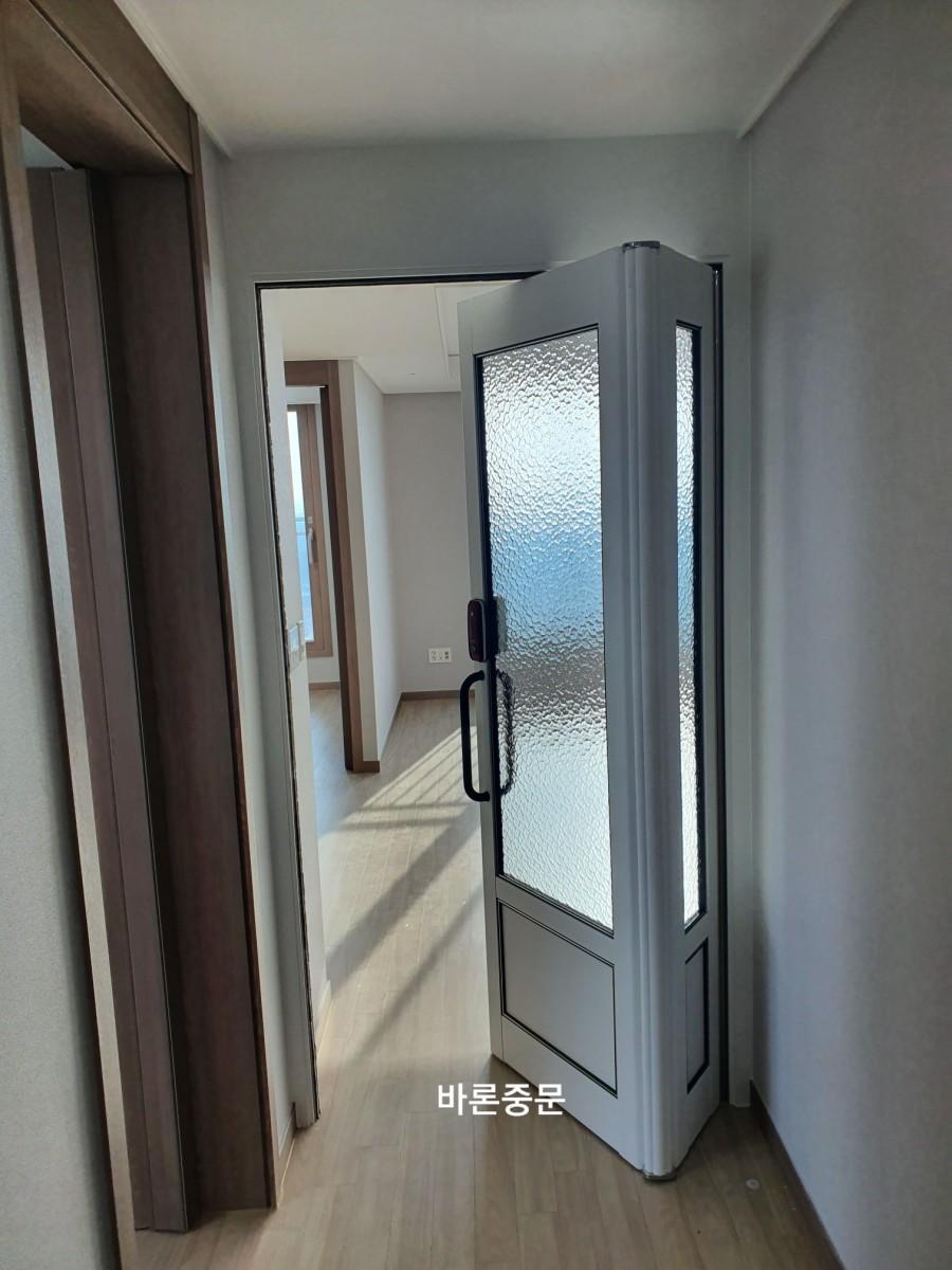 흰색 벽과 목재 바닥이 보이는 중문 설치 모습