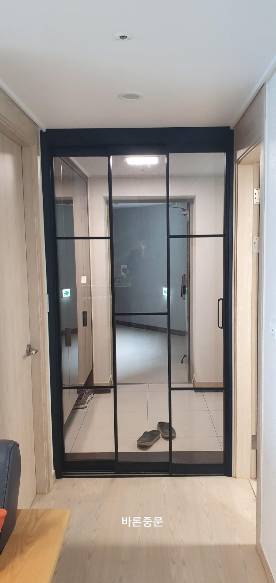 베이지색 목재 패널 벽면과 블랙 프레임의 대비
