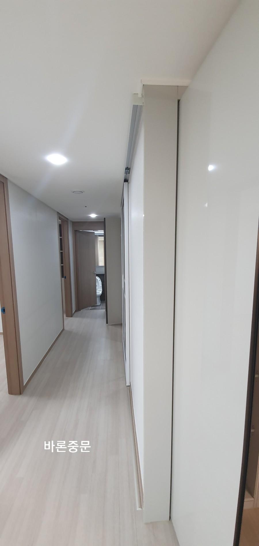 높은 수납장이 있는 복도의 밝은 바닥재와 벽면