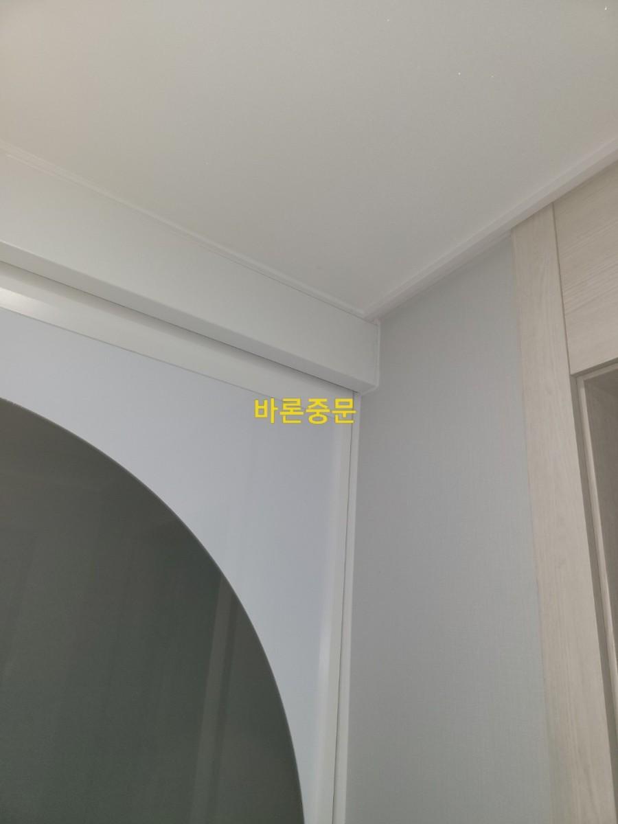 회색 벽면과 목재 도어 프레임의 정교한 접합부