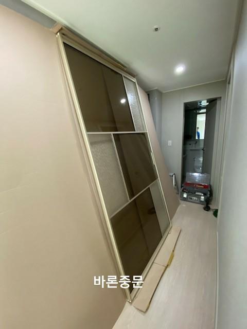 복도 벽면에 설치 중인 슬라이딩 도어와 유리 패널