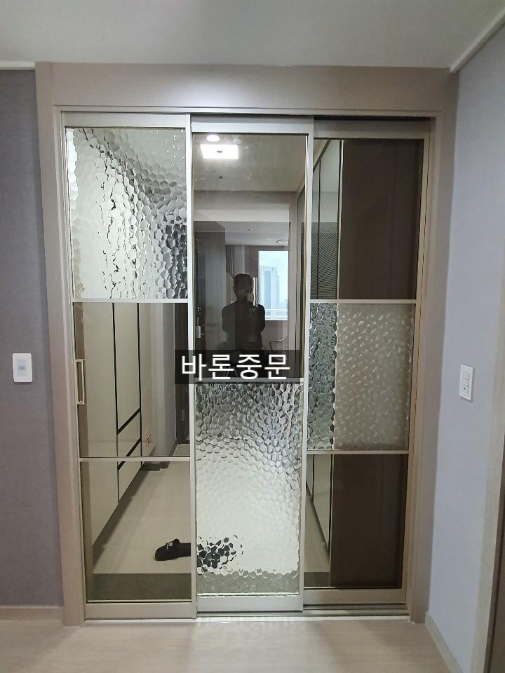 회색 벽지와 베이지색 마루가 만나는 복도의 슬라이딩 도어