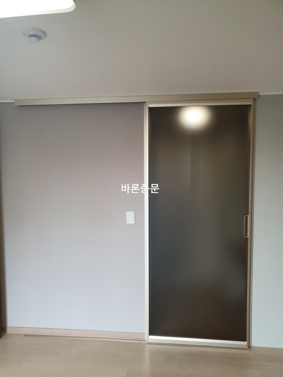 연한 회색 벽면에 설치 중인 슬라이딩 도어