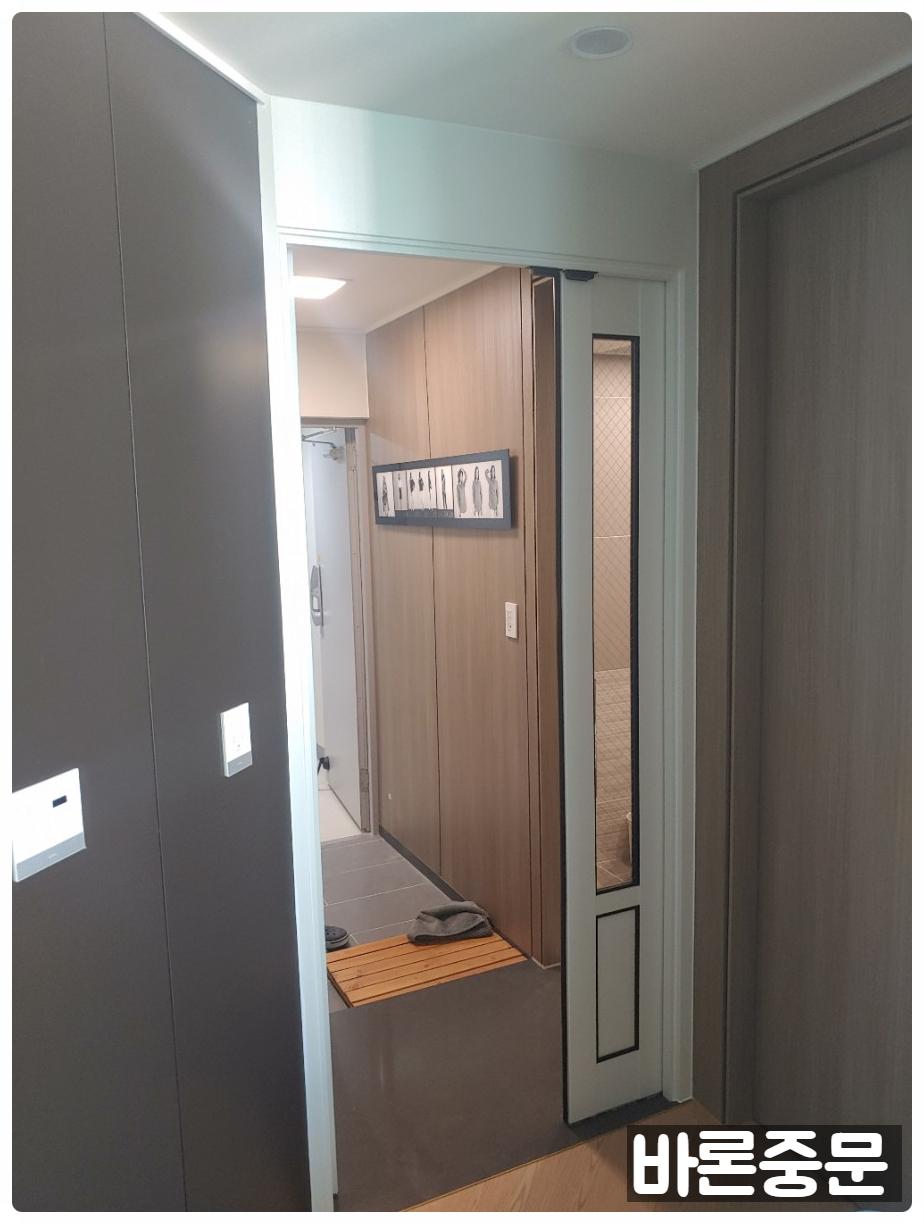나무 발판이 놓인 회색과 베이지 톤의 현관 입구