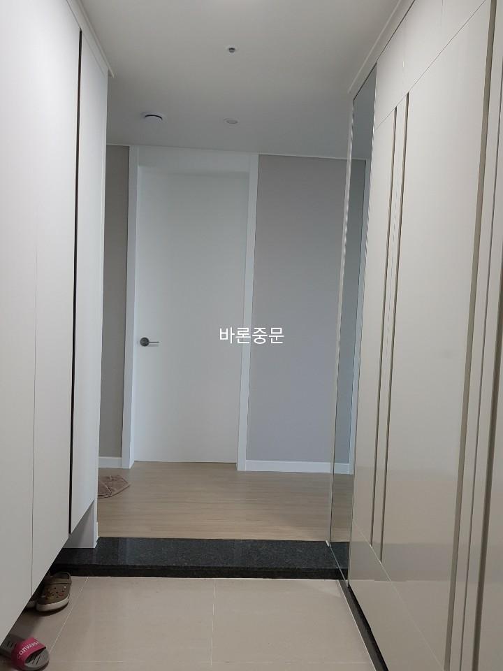 화이트 수납장과 검은색 타일 바닥이 조화로운 현관 전경