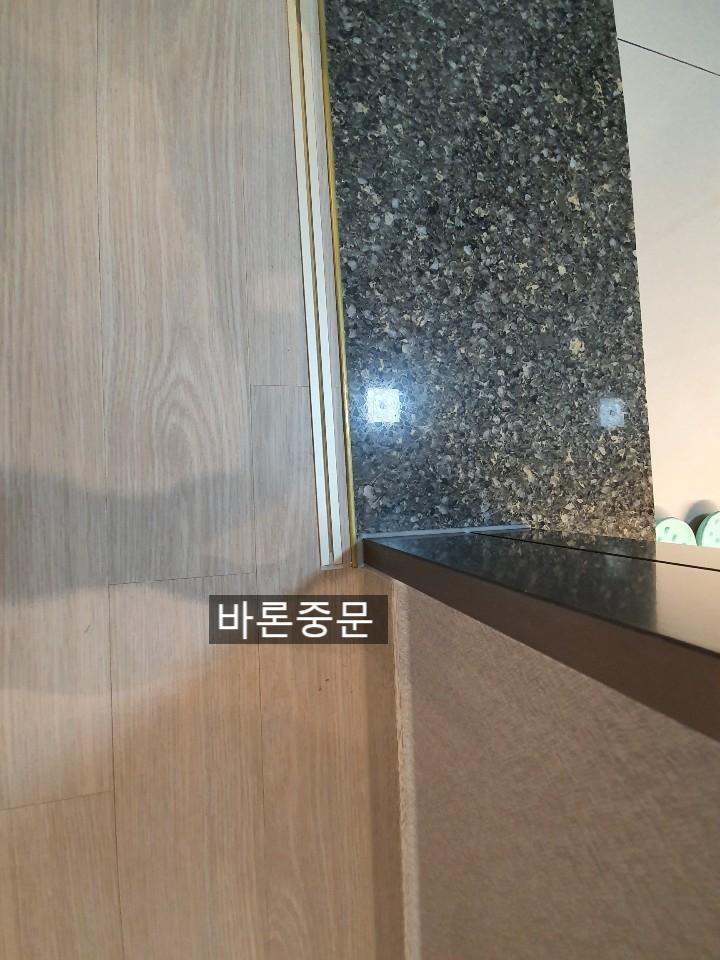 검은색 석재 상판과 목재 바닥재의 경계 마감