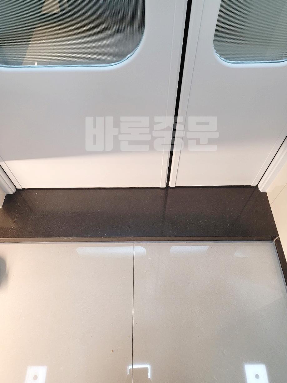 검은색 바닥재 위에서 설치 중인 화이트 도어