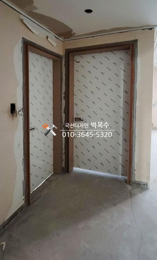 문틀 주변 벽면과 전기 스위치가 보이는 복도