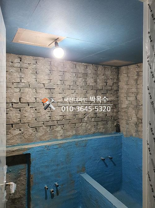 파란색 마감층과 배관이 노출된 벽돌 벽
