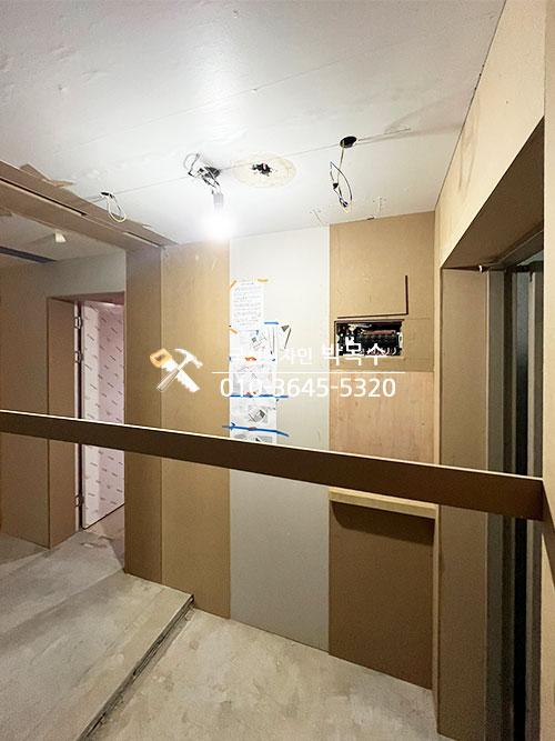 벽면에 보드와 전선이 노출된 콘크리트 바닥의 복도