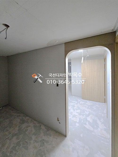 흰색 바닥재와 천장, 회색과 갈색 벽면이 보이는 복도