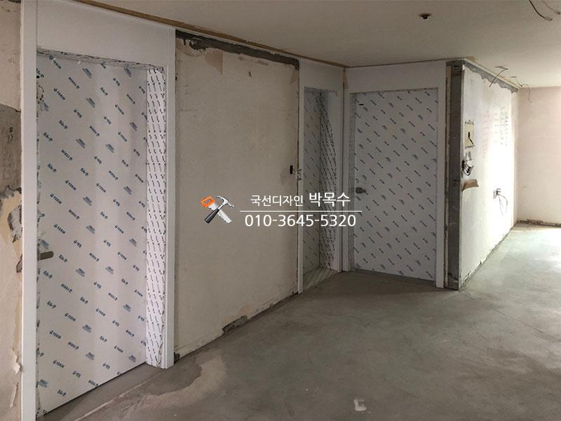 흰색 보드로 덮인 문과 콘크리트 바닥의 복도