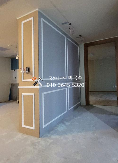 베이지와 회색 패널로 구획을 나눈 복도 벽면