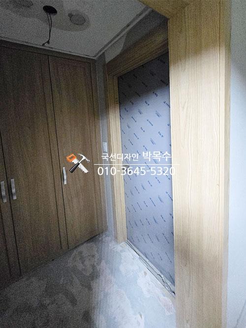 회색 벽지와 우드톤 수납장이 설치된 복도 모습