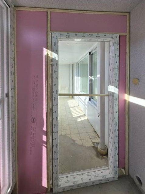 분홍색 벽지와 흰색 문 프레임이 보이는 복도 통로