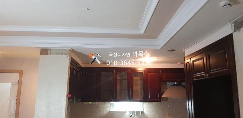 어두운 우드톤 붙박이장과 유리 문이 있는 주방