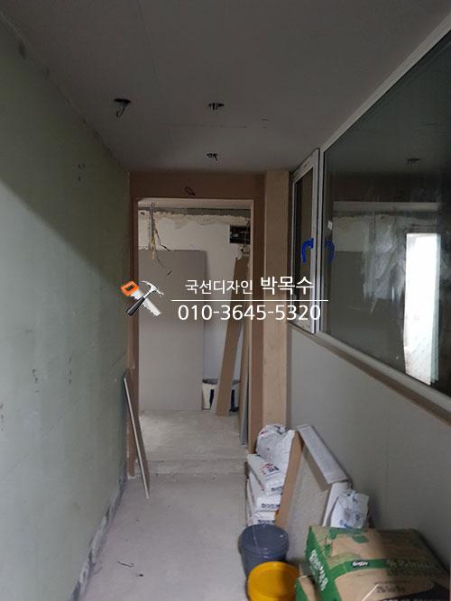 파란색 보호 테두리가 둘러진 창호와 정돈 중인 복도