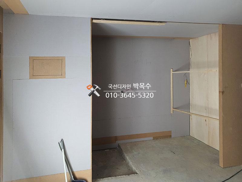 흰색 마감 벽면과 목재 패널이 부착된 공사 현장