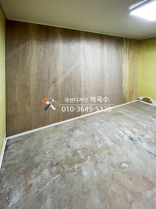 목재 패널 벽면과 텍스처 바닥이 마감된 실내