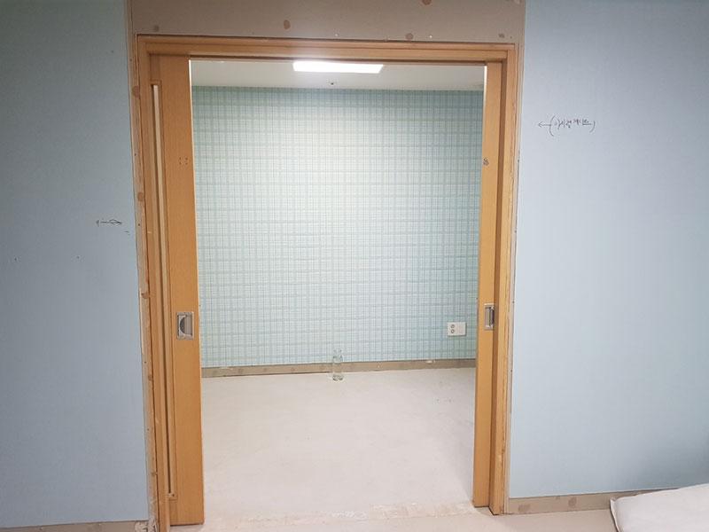 파란색 벽면과 체크무늬 벽지가 보이는 문 주변 모습